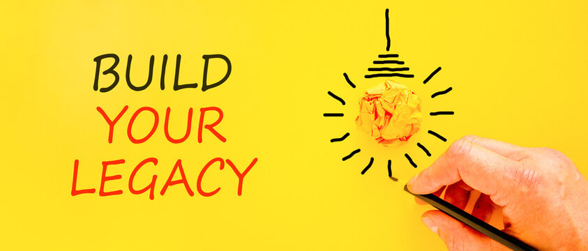 Build your legacy words symbol. Concept words Build your legacy on beautiful yellow paper. Beautiful yellow background. Businessman hand. Business build your legacy concept. Copy space.
