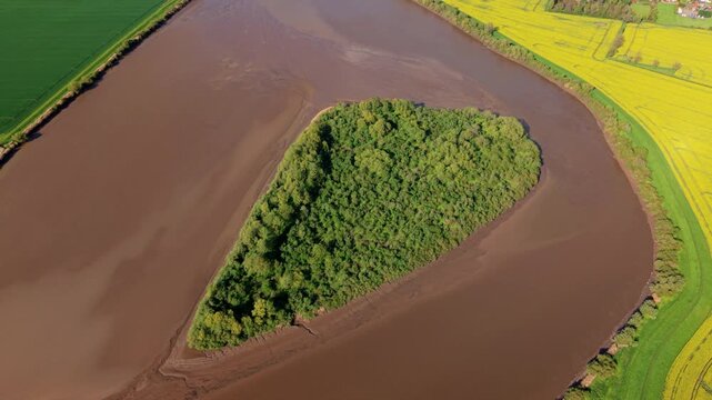 Aerial view of Howden Dyke Island surrounded by murky brown tidal waters of River Ouse in East Yorkshire UK