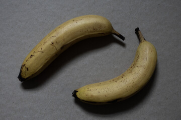 Two ripe yellow bananas on a gray surface creating a healthy fresh fruit concept © Pavlo