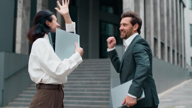 Two positive cheerful Caucasian middle-aged business workers happy dancing moving having fun in city carefree joyous woman and man dance businessman with businesswoman fooling around move in downtown