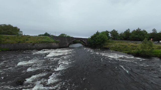 FPV drone flight down a Scottish river. Shot in Poolewe in the Highlands of Scotland the flight follows the course of the river flowing under a road bridge.