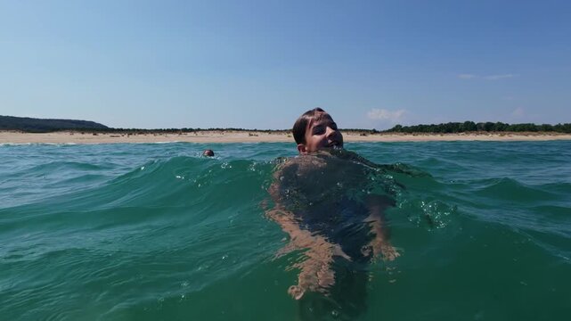 Two Boys Swimming and Playing in the Sea Water near Sandy Wild Beach