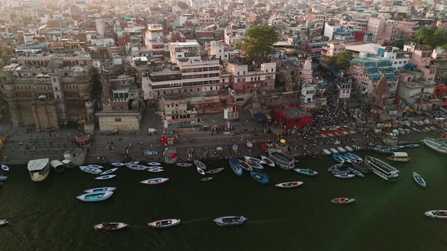Aerial view of varanasi city with boats on the ganges river and people at the ghats for ganga aarti ceremony at sunset