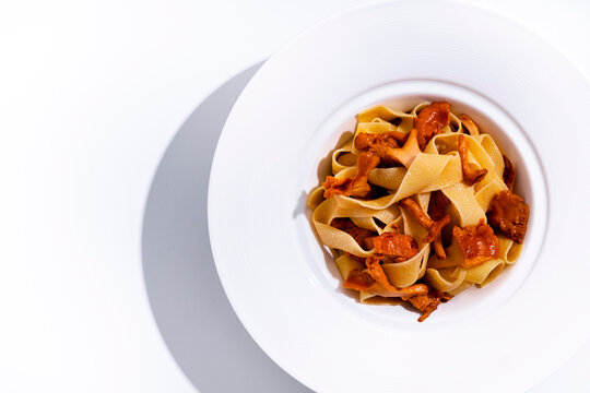 Delicious pasta with chanterelles on white plate - Italian food dish. Gourmet wild mushrooms meal rich in carbohydrates for dinner. Authentic vegetarian cuisine, healthy eating recipe.