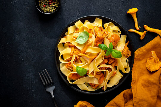 Vegetarian food - pasta chanterelles for dinner with raw ingredients. Seasonal culinary dark mood flat lay. Italian gourmet restaurant serving with yellow cloth and metal fork