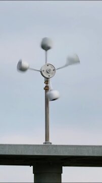 Close-up view of a modern wind turbine against a cloudy sky with blurred background showing the turbine's spinning blades and central hub