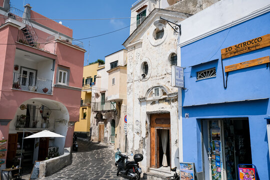 Procida, Italy - August 7, 2026. Historic Weathered Chapel and Cobblestone Street in Procida. A close-up view of a charming, weathered historic chapel facade along a narrow cobblestone street on the i