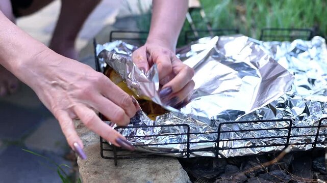Potato is arranged with spices and herbs in foil covered baking tray during meal preparation. Vegetable ingredient highlights family gathering and comfort food concept. Potato awaits golden roasting.
