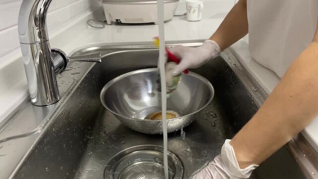 Rinsing a freshly cleaned abalone under running tap water in a sink