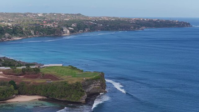 Balangan cliff promontory with breaking surf and receding coastline under clear daylight, with coastline, cliff, ocean, surf detail, showing wave, shoreline, promontory, headland context