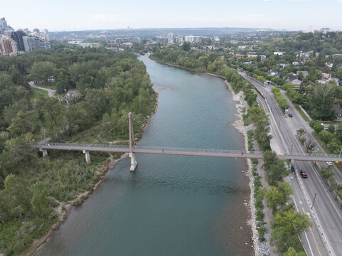 aerial landscape view along Bow River with Bow River Pathway Bridge at Memorial Dr and Prince&rsquo;s Island Park, next to Downtown Calgary ( Alberta, Canada) with Sunnyside district on right river bank and