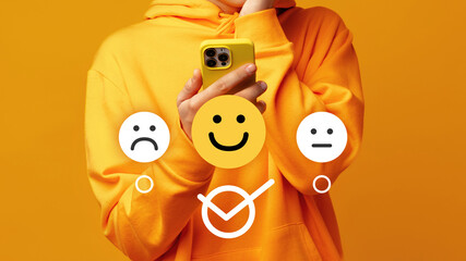 Person holding a smartphone while standing against a yellow background looking thoughtful about a...