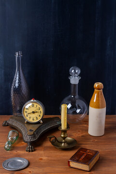 Various old vintage objects on brown wooden table by the black wall. Still life.