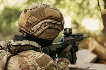 Obraz premium Armed military operator aiming a rifle during a combat patrol mission. Back view