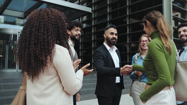 Indian business man shaking hands with company partner in front of modern office buildings 