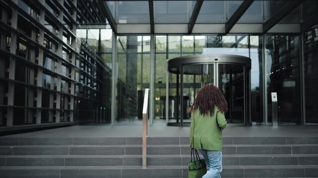 Young African American professional woman arriving to the office in a busy business district