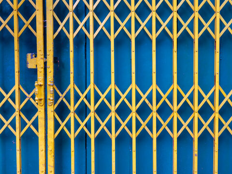 Vibrant Yellow Folding Metal Gate on Teal Shophouse Door