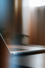 Laptop sits on a table near a window in soft light during the day