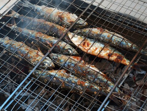 Fresh fish grilling over hot charcoal on a barbecue wire grate with barbecue
