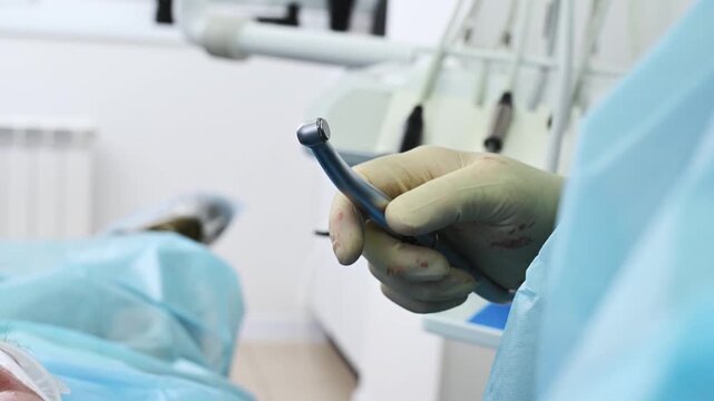A dentist inserts a burr into a contra-angle handpiece to prepare a bone bed for an implant or to work with an implant system during a dental implant placement procedure. Close-up, face removed.