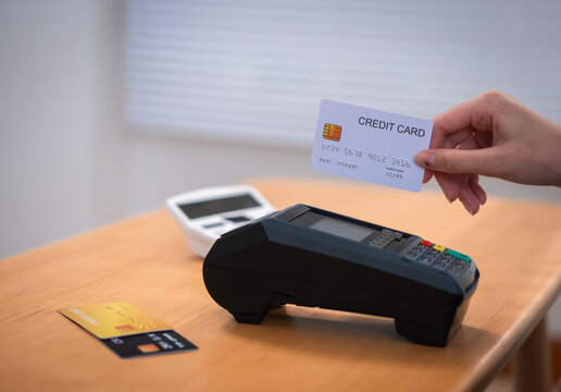 Credit card financial payment terminal personal wealth planning with hand holding card during secure purchase transaction at wooden counter