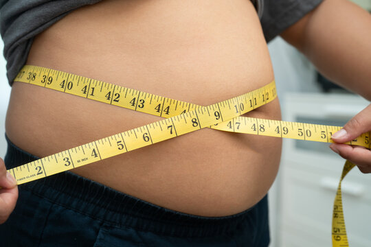 Asian woman with fat belly big size overweight and obesity with measure tape.