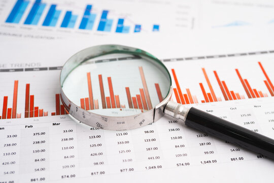Magnifying glass on data business graphs paper.