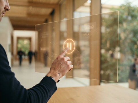 Man tapping a transparent display on a wooden table in a modern hall seen up close