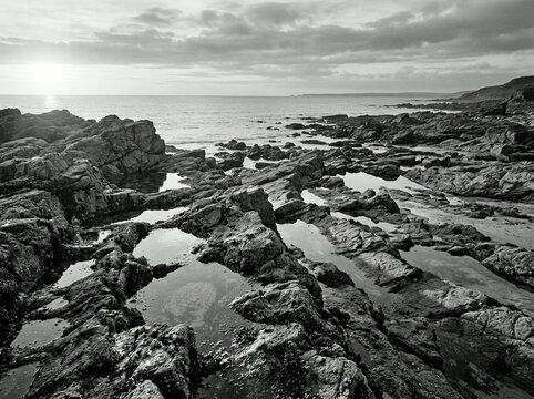 Rocky coastline with tide pools and ocean horizon in dramatic black and white landscape photography