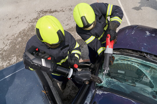 Firefighters Using Hydraulic Rescue Tools To Extricate Driver From Crashed Car During Emergency Response Training