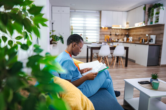 African american woman studying at home wearing scrubs