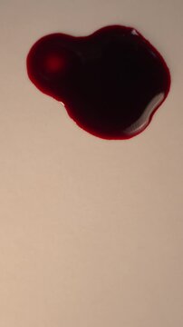 Blood dripping and impacting pool on light surface for crime scene evidence, top view slow motion, bottom copy space, vertical video