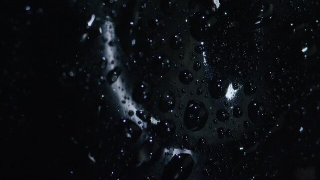 Abstract macro shot of water droplets on glossy black surface