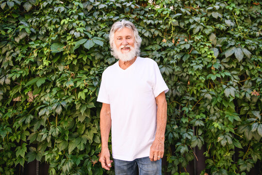 Senior man in the city park having great time close to a vegetable wall
