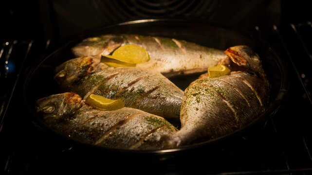 Whole fish roasting with lime slices in oven pan under warm amber light, bubbling juices and crisping skin, with fish, roasting, oven, pan detail, showing lime, slice, cooking, bubbling context