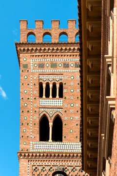 Mudejar tower of San Martin close up detail, Teruel Spain. Historic brick architecture with green glazed ceramic tiles and arches under blue sky. High quality photo