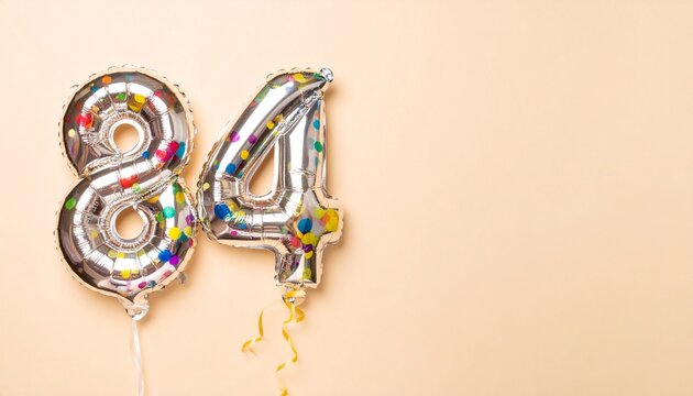 Silver foil balloons forming number 84 with colorful confetti inside