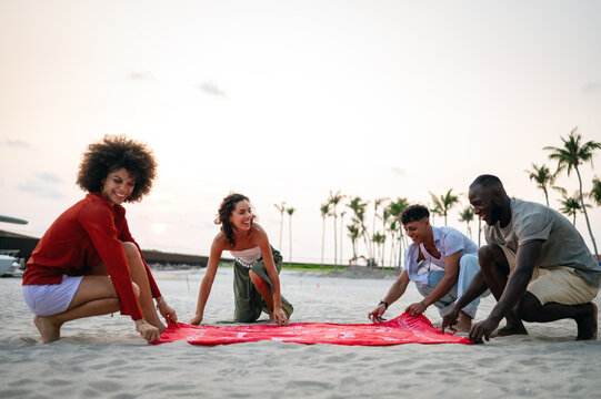 Relaxed golden hour lifestyle of young friends on a tropical beach, enjoying the warm sunset