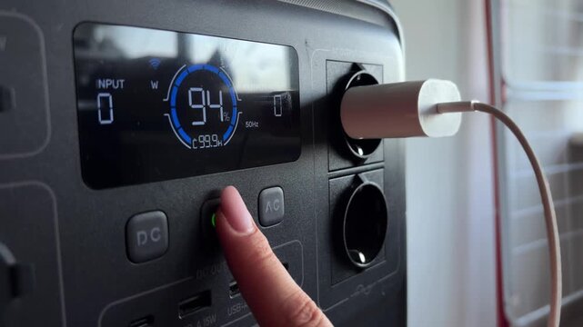 Portable power station shutdown sequence with a hand pressing the buttons and unplugging the charger, showcasing modern off grid energy storage and sustainable technology