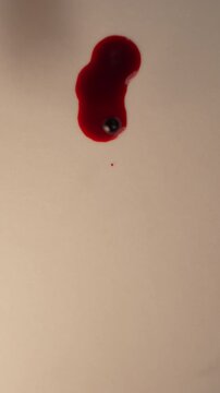 Fresh blood drop falling onto empty cream background for forensic evidence, top view close up slow motion, bottom copy space, vertical video