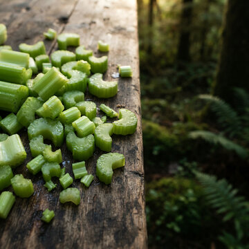 Chopped celery scattered on weathered wood before a dense green forest
