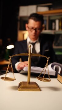 Scales of Justice with Blurred Lawyer Reading Document in Law Office