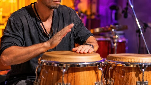 Close-up of a musician's hands playing wooden conga drums on stage during a live percussion performance