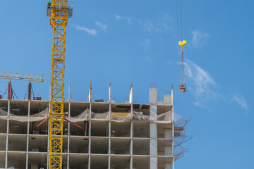 Construction of a high-rise building showcasing the dynamic process of urban development against a vibrant blue sky © beholdereye