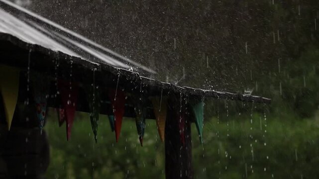 Heavy rain falling onto a rustic wooden roof under cloudy skies, slow motion
