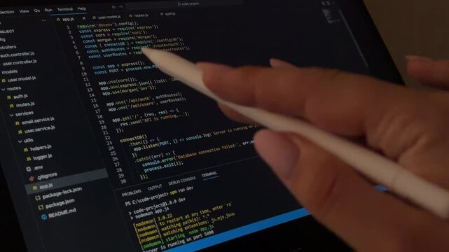Web developer reviewing javascript code on a tablet with a stylus pen, highlighting and analyzing the script while working on a software development project from home