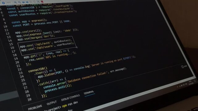 Software engineer coding a server side application using javascript on a laptop, close up view of the programmer writing code and connecting to a database for web development