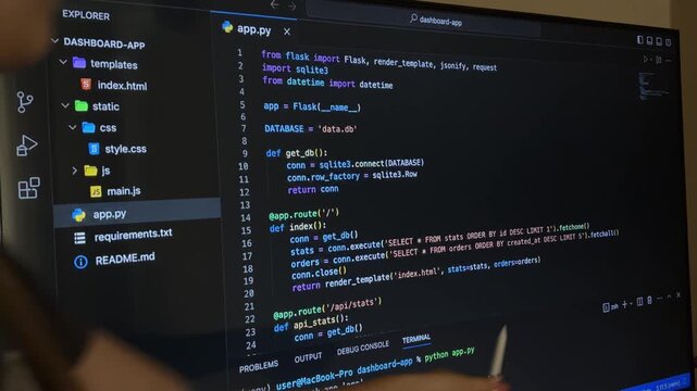 Female programmer explaining python code for a web application, pointing at the screen with a stylus during a presentation or lesson on software and web development