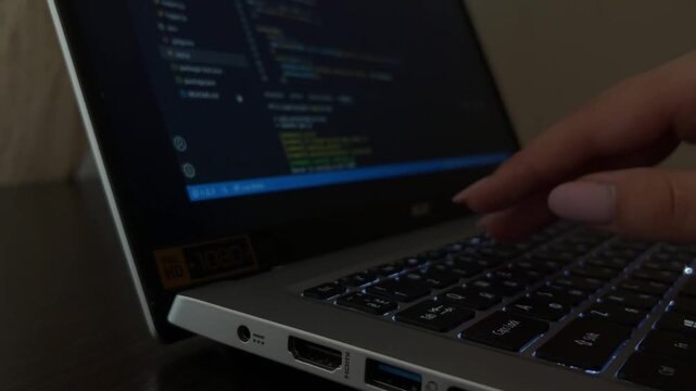 Female programmer's hands coding on a laptop keyboard at night, close up of web developer writing source code and software engineer working with javascript