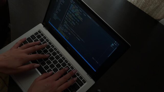 Female programmer typing code on laptop keyboard at night, software developer working remotely from home office, freelancer developing website and programming app